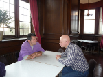 Two men facing each other across a dining table